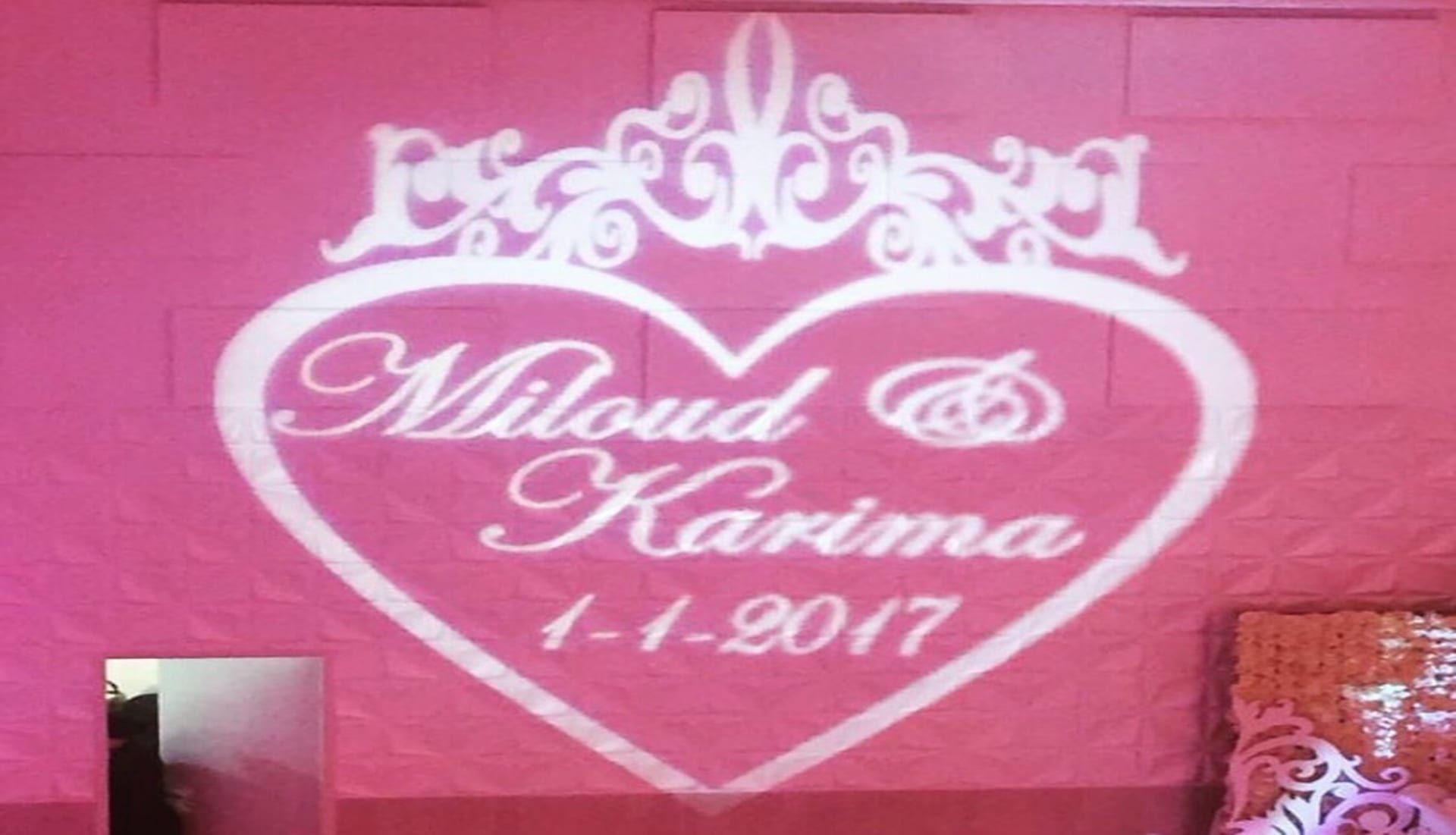Hartvormige gobo met kroon, de namen Miloud & Karima en de trouwdatum op een roze wand